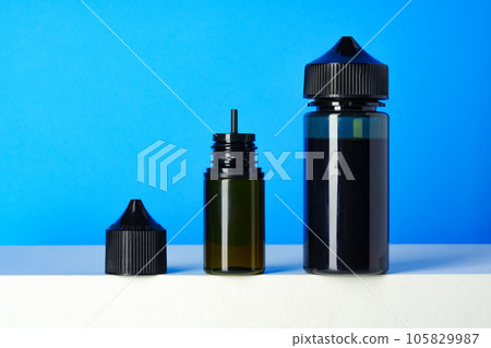Black electronic cigarettes liquid bottles on blue background 105829987