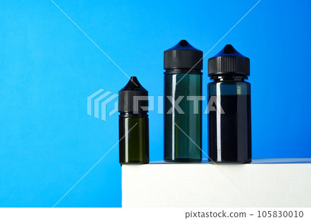Black electronic cigarettes liquid bottles on blue background 105830010