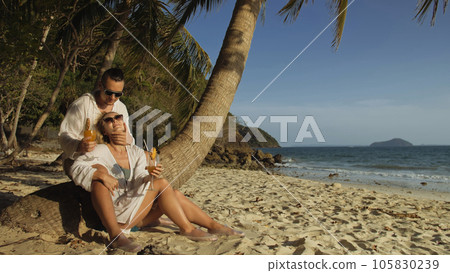 Loving couple in white dress and sunglasses, near palm tree, rel Loving couple in white dress and sunglasses, near palm tree, rel 105830239