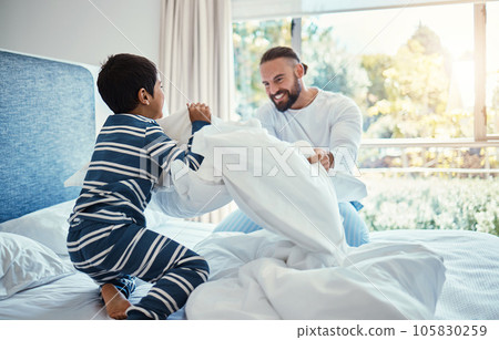 Love, father and son in bedroom, pillow fight and happiness on vacation, quality time and break. Family, dad and boy on bed, playful and smile for bonding, loving and carefree with joy and cheerful 105830259
