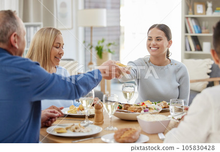 Could you pass the potatoes. a family having lunch together at home. 105830428