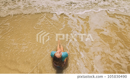 Woman lying on shallow water sea. Happy slightly tipsy woman enj Woman lying on shallow water sea. Happy slightly tipsy woman enj 105830490