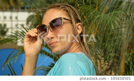 Woman taking a shower in garden near hotel. Girl in blue swimsui Woman taking a shower in garden near hotel. Girl in blue swimsui 105830501