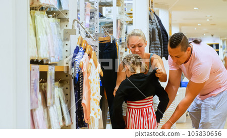 Beautiful family father mother and daughter shopping in clothes shop.Dad and mom with her little child shopping shirt in clothing store.Happy loving family choose looking for clothes in shopping mall. Beautiful family father mother and daughter shopping in clothes shop.Dad and mom with her little child shopping shirt in clothing store.Happy loving family choose looking for clothes in shopping mall. 105830656