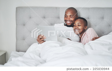 Tablet, bedroom and a black couple streaming an online subscription service while in their bed together to relax. Social media, entertainment or video with a man and woman relaxing in the morning 105830944