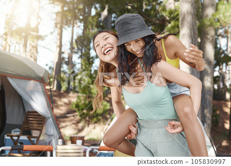 Friends, camping and women piggy back in nature for adventure, freedom and holiday outdoors. Friendship, happy and people laughing in woods, forest and mountain for travel, vacation and trekking 105830997