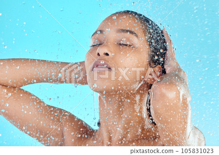 Water drops, face cleaning and black woman shower with liquid for hydration, beauty healthcare or skincare hygiene. Self care studio, spa salon or relax model washing body isolated on blue background Water drops, face cleaning and black woman shower with liquid for hydration, beauty healthcare or skincare hygiene. Self care studio, spa salon or relax model washing body isolated on blue background 105831023
