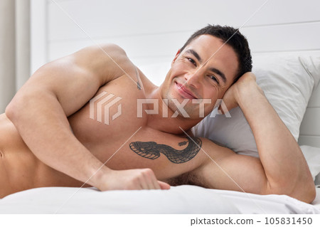 Woke up on the right side of the bed. a handsome young man lying in bed. 105831450