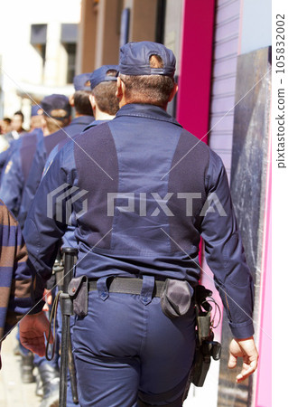 Police, group and walking in city for safety, law enforcement and urban patrol from the back. Security, team of people and public service cops with legal power, authority and crime guard in street 105832002