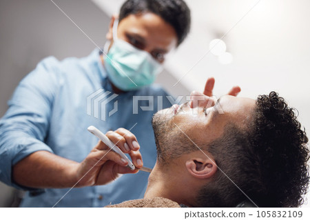 Time for a shave. a handsome young man getting groomed by a barber. 105832109