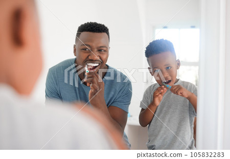 Black man brushing his teeth with his kid for dental hygiene, health and wellness in the bathroom. Oral care, teaching and young African father doing morning mouth routine with his boy child at home. 105832283
