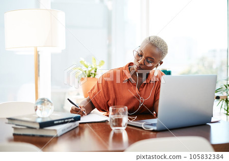 Dream big and do bigger. Shot of a young businesswoman wearing earphones while writing notes in an office. Dream big and do bigger. Shot of a young businesswoman wearing earphones while writing notes in an office. 105832384