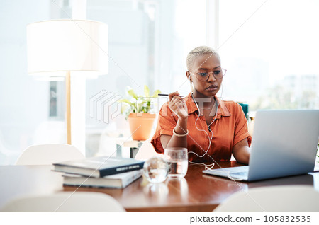 A goal is a dream with a deadline. Shot of a young businesswoman wearing earphones while working on a laptop in an office. 105832535