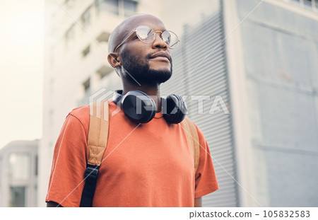 .Black man, student and walking outdoor on a city street while thinking of music and freedom. A serious African person with a backpack on an urban road with casual style and fashion for travel. 105832583