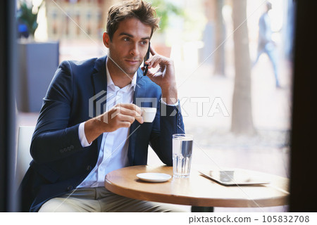 Business even when on break. Shot of a young businessman enjoying a cup of coffee and talking on the phone. 105832708