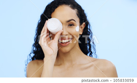 Face, cream jar and beauty of woman, cosmetics and smile on blue background. Facial lotion, skincare and portrait of happy studio model with container for shine, natural wellness and aesthetic makeup 105833059