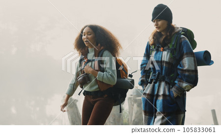 Travel, backpack and friends hiking in the mountain on a cold, overcast morning in nature together. Travel, freedom and adventure with women walking in the wilderness to explore while bonding 105833061