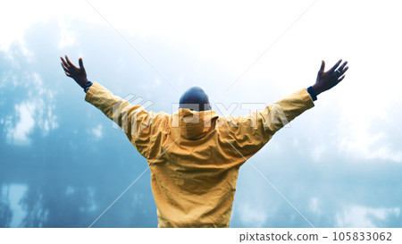 Man, freedom and arms raised outdoor in nature to relax and breathe fresh air. Vacation, woods or forest with a person on holiday or hike on misty morning for victory or travel success from behind Man, freedom and arms raised outdoor in nature to relax and breathe fresh air. Vacation, woods or forest with a person on holiday or hike on misty morning for victory or travel success from behind 105833062