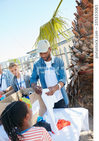 Giving back is the best gift you could give. Shot of volunteer workers handing out clothing to underprivileged kids. 105833065