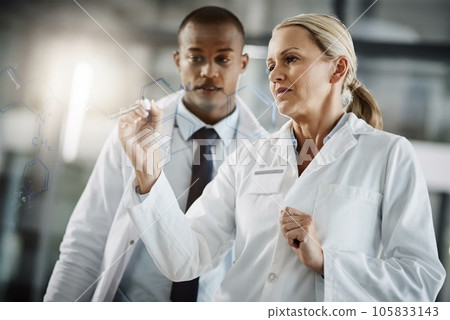Working out the perfect formula. Cropped shot of two scientists writing down formulas on a glass wipe board while doing research in their lab. 105833143