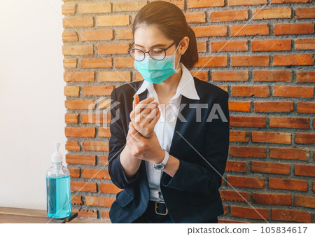 Businesswoman cleaning her hands by using hand sanitizer gel before working in office. Businesswoman cleaning her hands by using hand sanitizer gel before working in office. 105834617