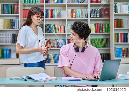 Woman mentor teaching male student in college library, exam preparation Woman mentor teaching male student in college library, exam preparation 105834955