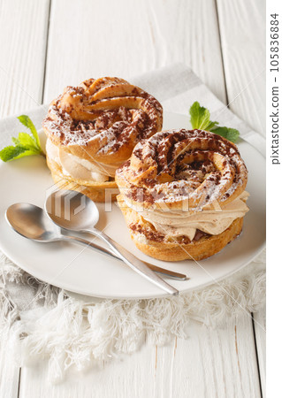 Paris-Brest is a French dessert made of choux pastry and a praline flavoured cream closeup on a plate. Vertical Paris-Brest is a French dessert made of choux pastry and a praline flavoured cream closeup on a plate. Vertical 105836884