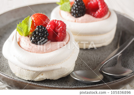 Homemade mini meringue Pavlova cake with berries and whipped cream closeup on a plate. Horizontal Homemade mini meringue Pavlova cake with berries and whipped cream closeup on a plate. Horizontal 105836896