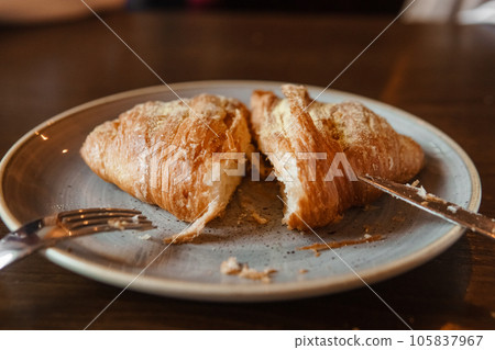 Cutting a croissant on a plate, close-up 105837967