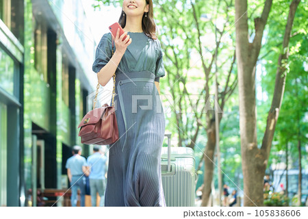 一個女人帶著手提箱在城市裡行走 105838606