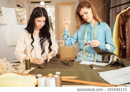 Seamstresses sew fabric by hand, sweep away details of future outfit. Work process, crafting, workplace. Seamstresses sew fabric by hand, sweep away details of future outfit. Work process, crafting, workplace. 105840153