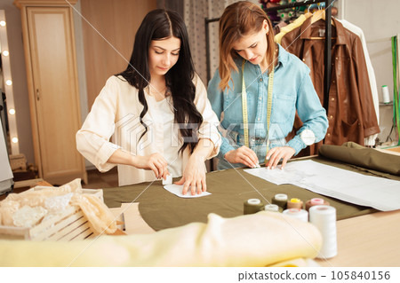 Seamstresses make sketch, pattern on fabric. Atelier, tailoring of individual clothes, small business. process of work in workplace 105840156