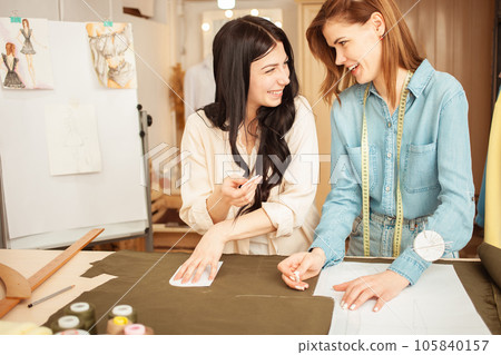 Seamstresses make sketch pattern on fabric. Atelier, tailoring of individual clothes, small business. laughing, cheerful, lifestyle 105840157