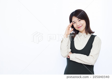A woman in her thirties thinking with a smile in front of a white background 105840340