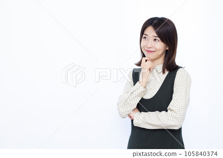 A woman in her thirties thinking with a smile in front of a white background 105840374