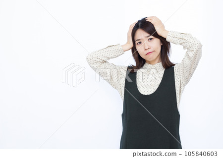 A woman in her thirties who is worried about holding her head in front of a white background 105840603