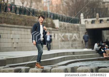 a young man with a camera in a park with a river 105840622