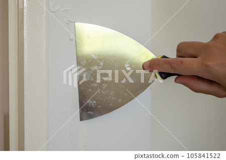 Man repairing crack white wall with spatula Man repairing crack white wall with spatula 105841522