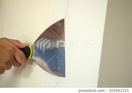 Man repairing crack white wall with spatula 105841525