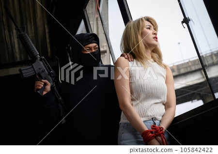 Masked criminal with gun and women as hostages standing looking out of window Masked criminal with gun and women as hostages standing looking out of window 105842422