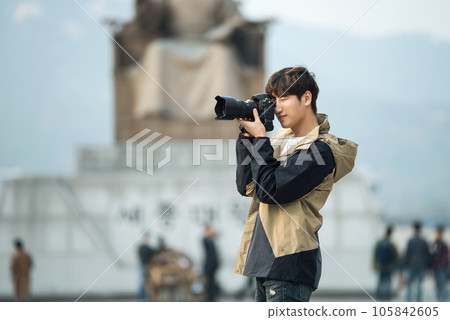 A young man holding a camera and taking pictures during a trip to Korea 105842605