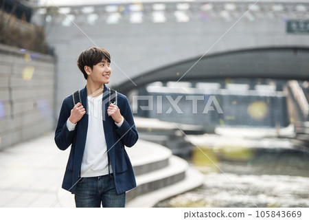 a young man taking a walk in a park with a river in the city 105843669