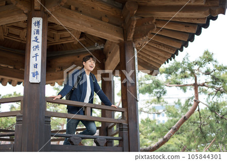 A young man doing a backpacking trip in a Korean traditional house. A young man doing a backpacking trip in a Korean traditional house. 105844301