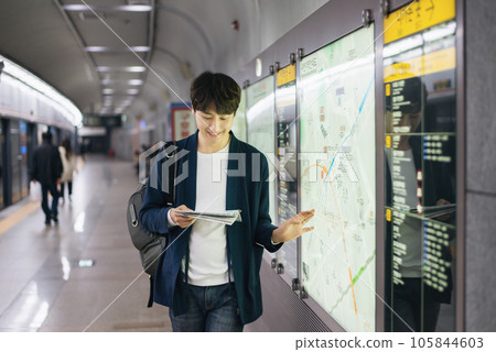 a young man holding a map at a train station 105844603