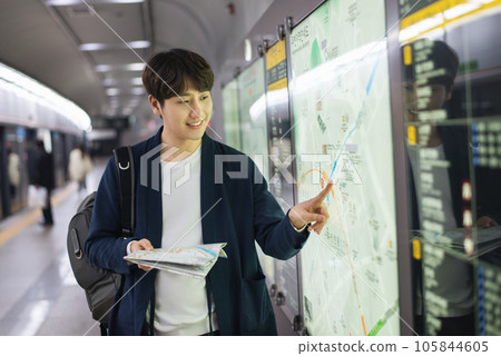a young man holding a map at a train station a young man holding a map at a train station 105844605