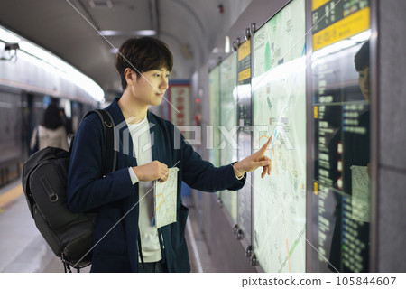a young man holding a map at a train station a young man holding a map at a train station 105844607