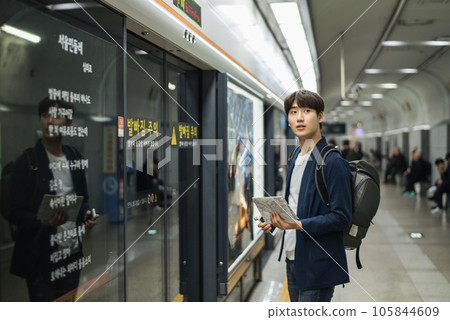 a young man holding a map at a train station a young man holding a map at a train station 105844609