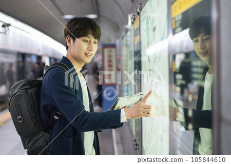 a young man holding a map at a train station a young man holding a map at a train station 105844610