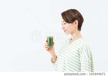 Middle-aged woman drinking green juice Middle-aged woman drinking green juice 105844671