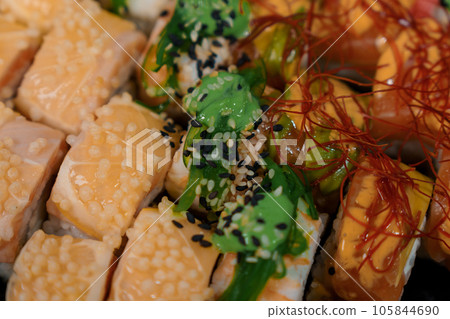 Rolls with red fish, rice, avocado, saffron. Set of rolls in a plate on a white background Rolls with red fish, rice, avocado, saffron. Set of rolls in a plate on a white background 105844690